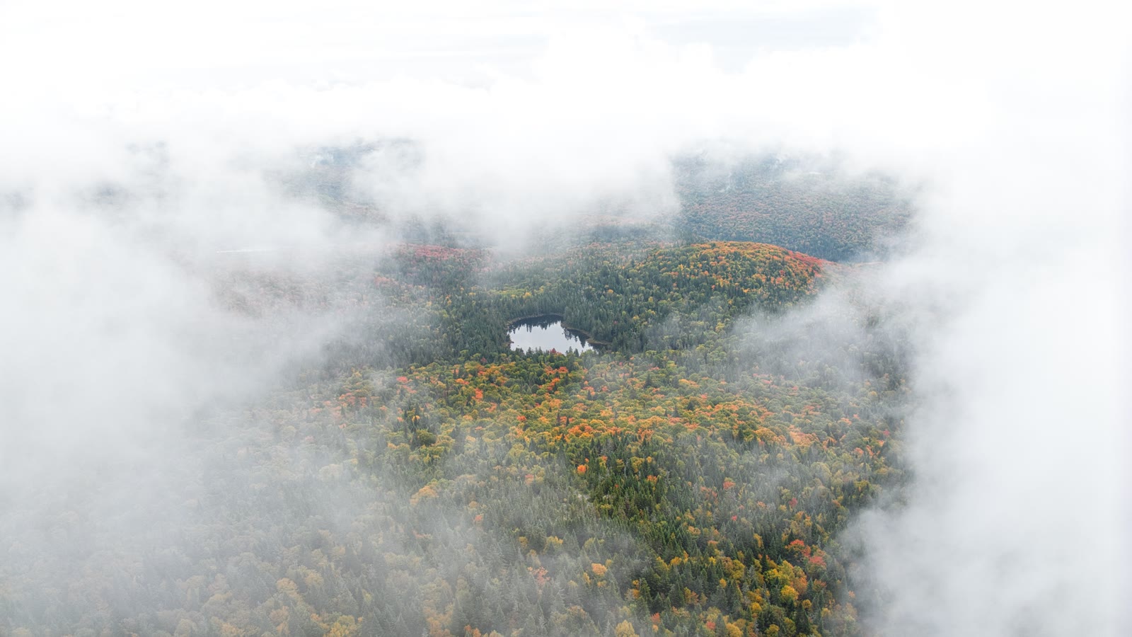 Vue aérienne d'un lac dans les Laurentides, forêt d'automne dans la brume